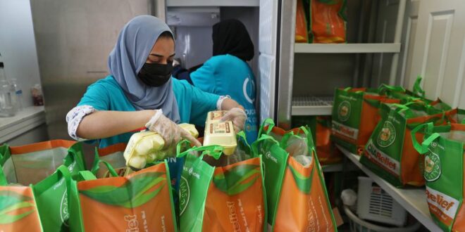 Relawan Safeera Khan memasukan makanan dan daging halal ke kantung kantung yang akan dibagikan kepada keluarga yang membutuhkan